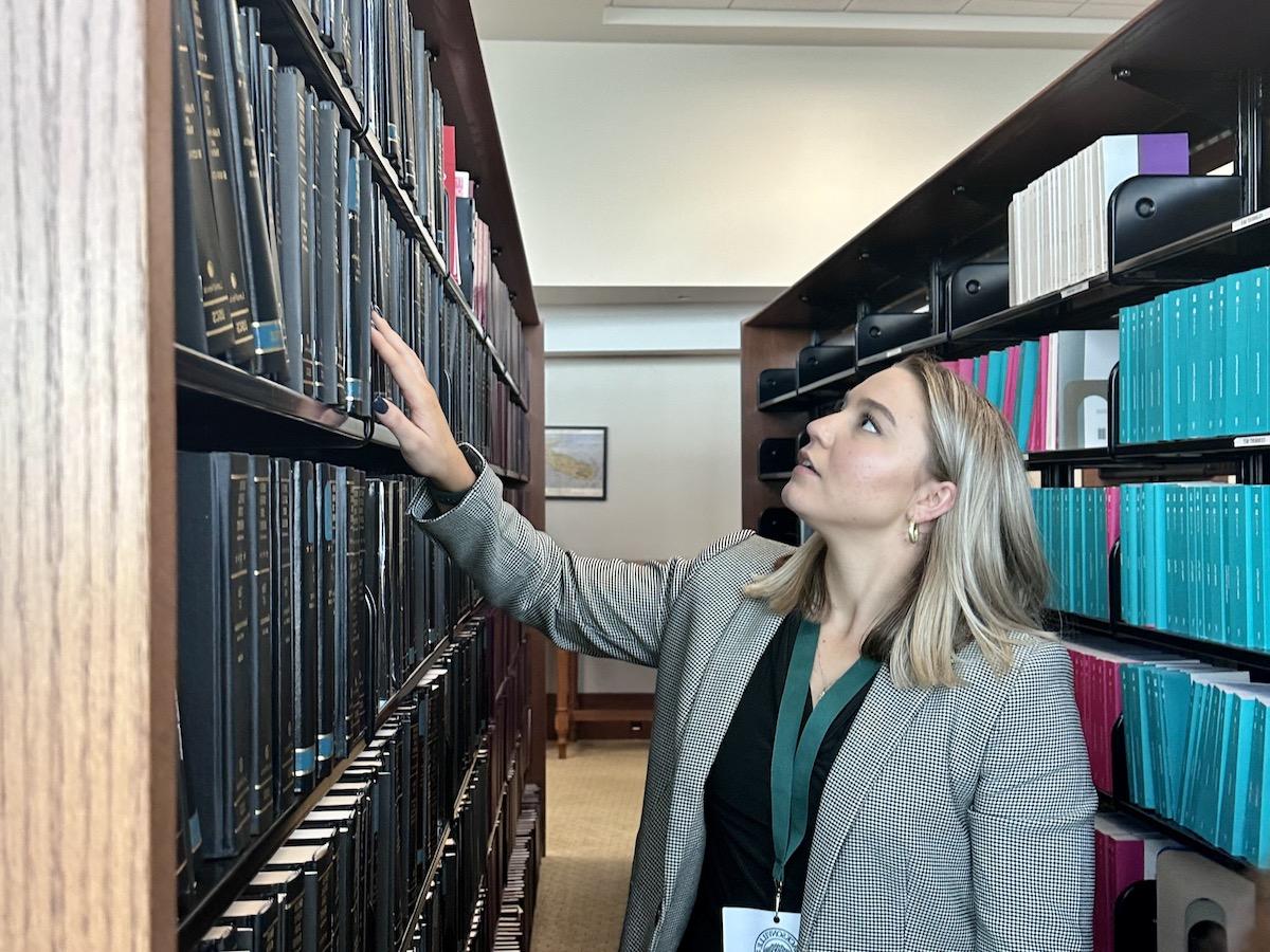 A female student reaching for a book in a courthouse library.